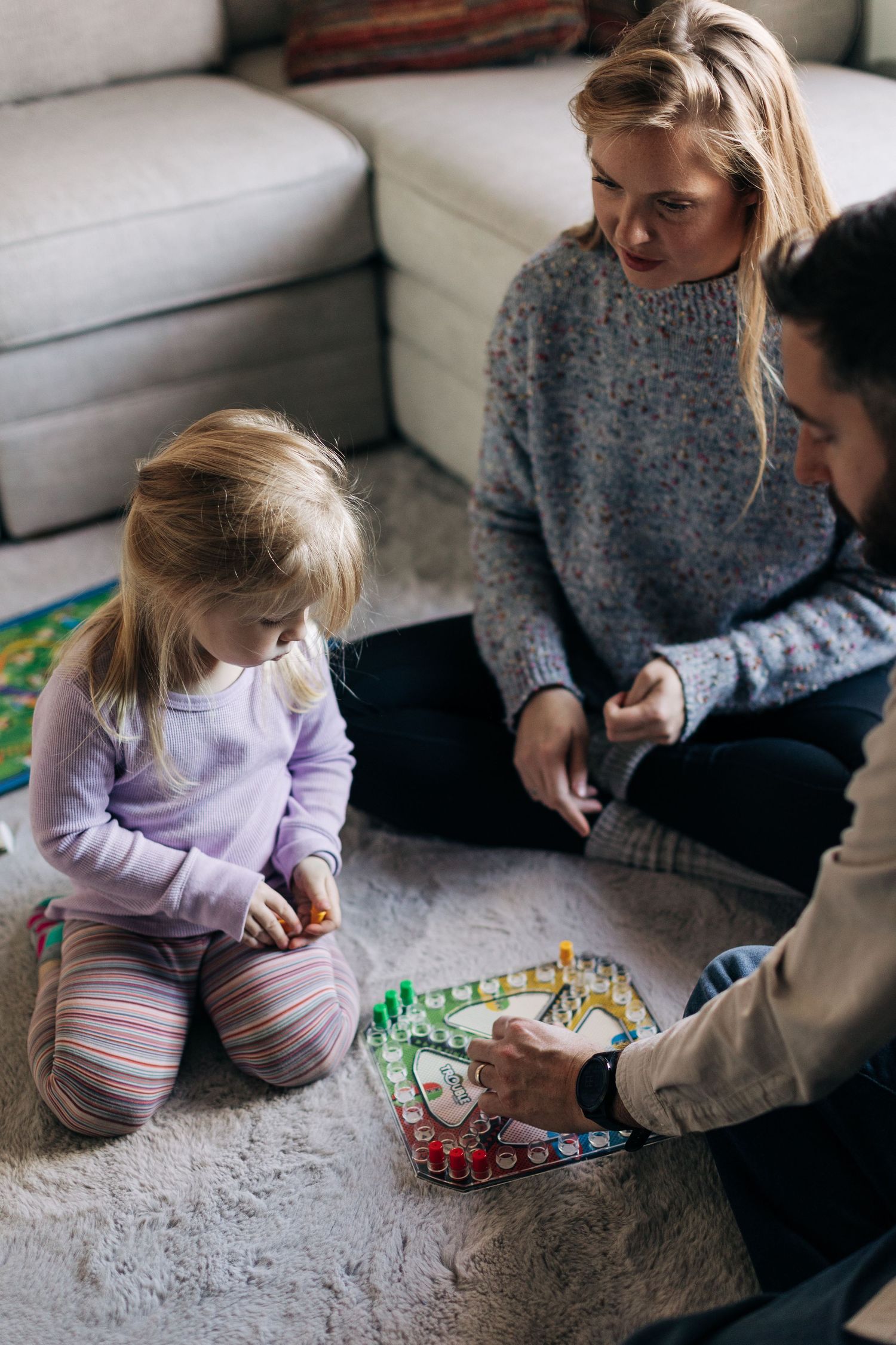 Family playing with toys together on living room floor.