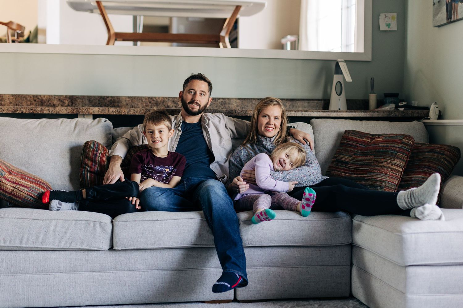 Family relaxing together on a comfortable grey sectional sofa in a cozy living room.