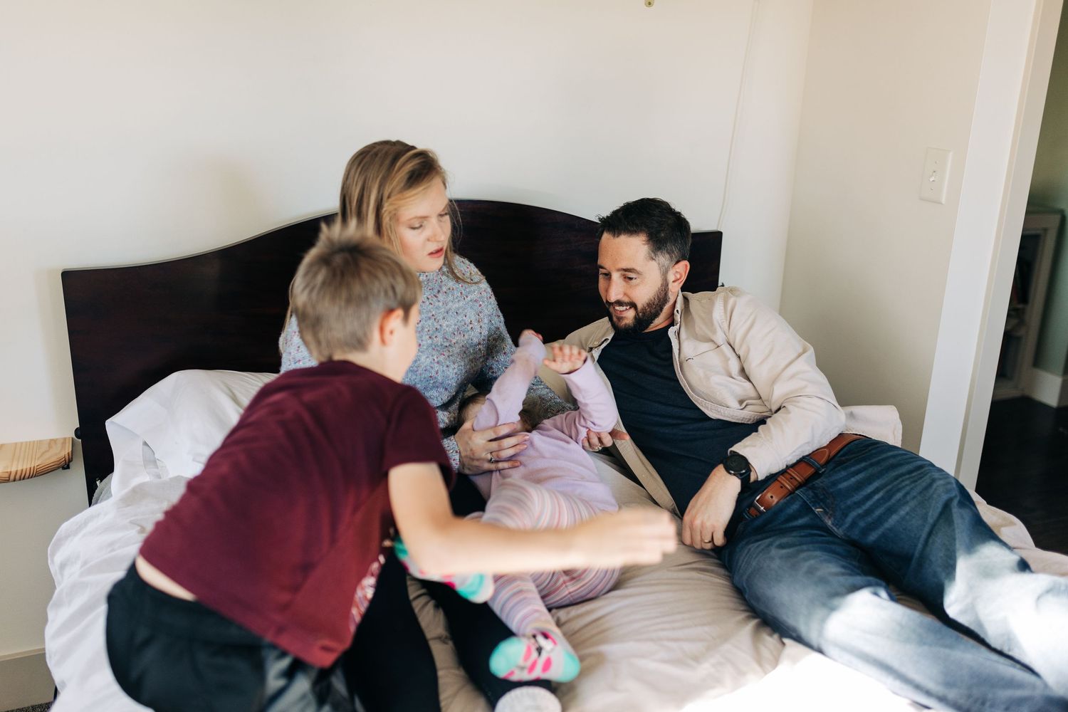 Family gathering on bed having a fun playful moment together.