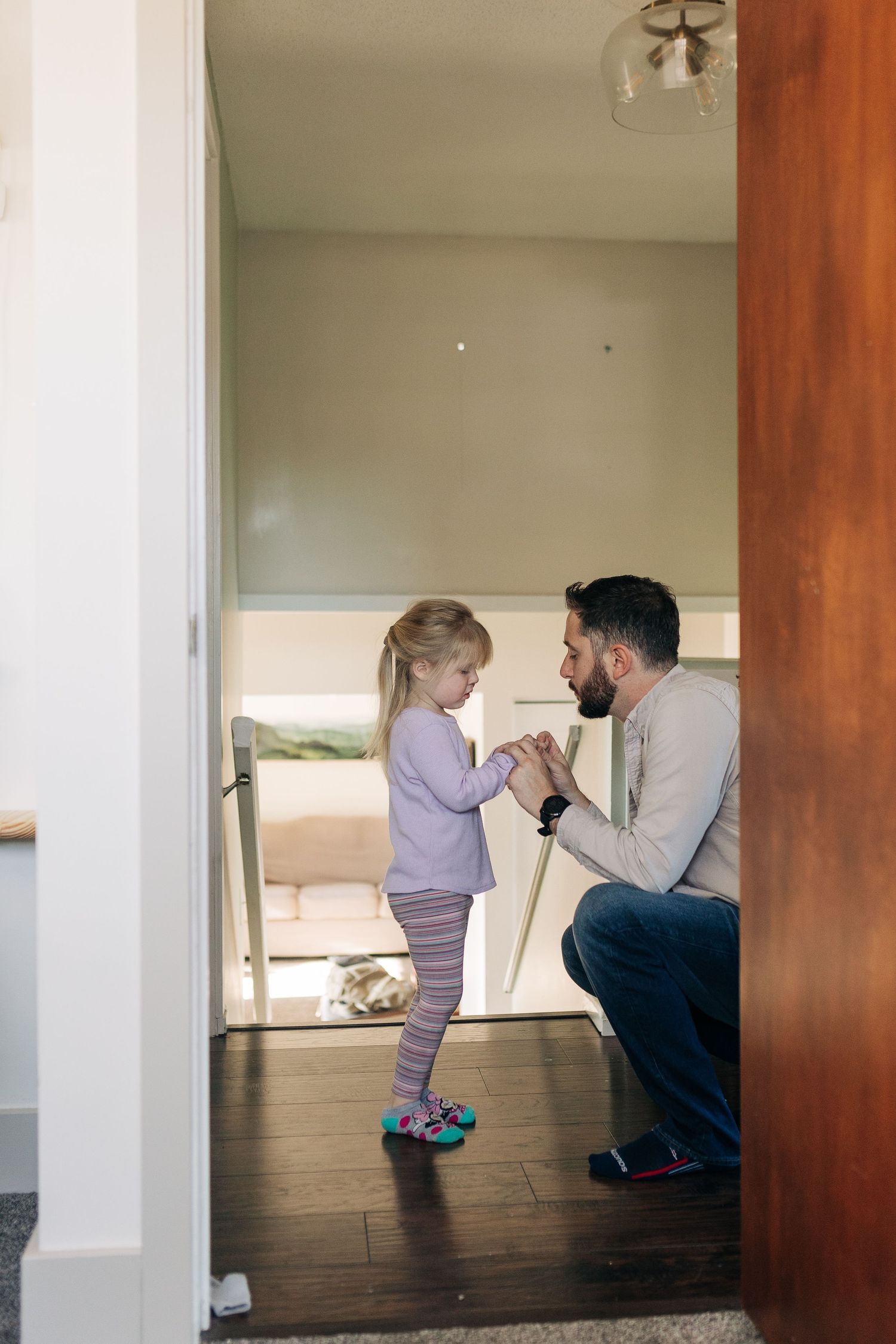 Sweet moment shared in hallway with hardwood floors and mint green walls.