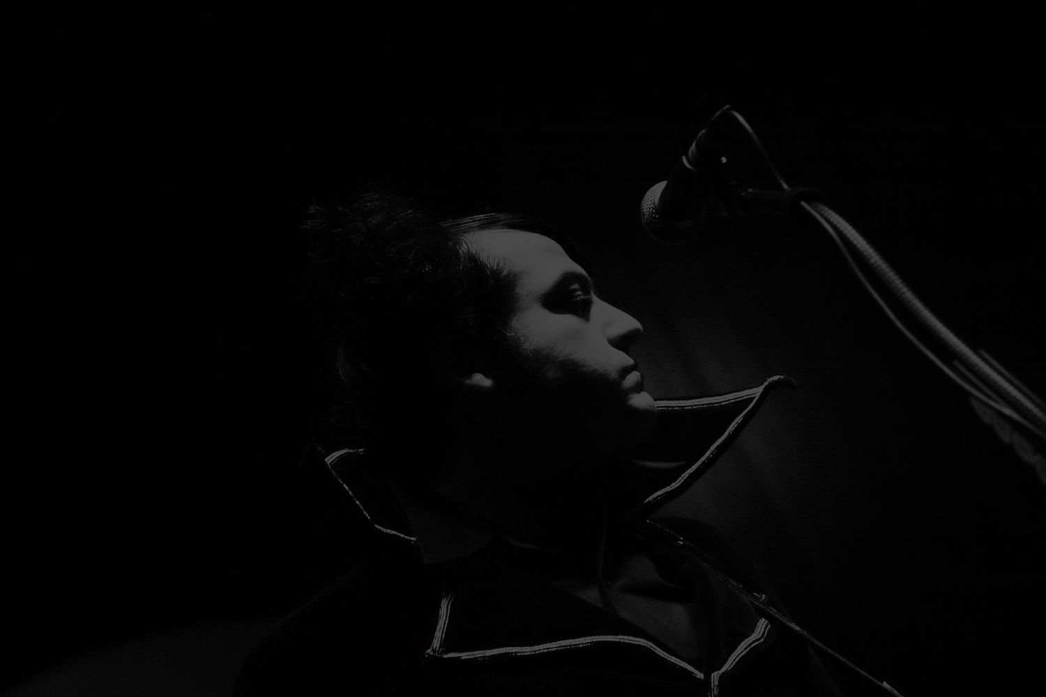 Dramatic low-key black and white performance photo captured in dark moody lighting.