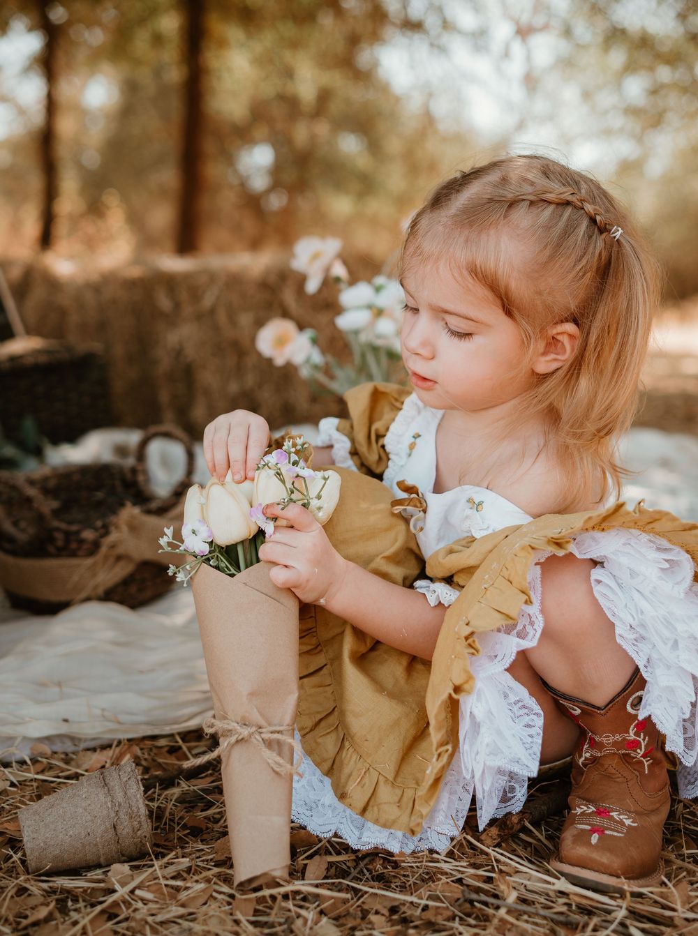 A series of photos showing a child in vintage-inspired clothing playing with delicate white flowers in a natural setting.