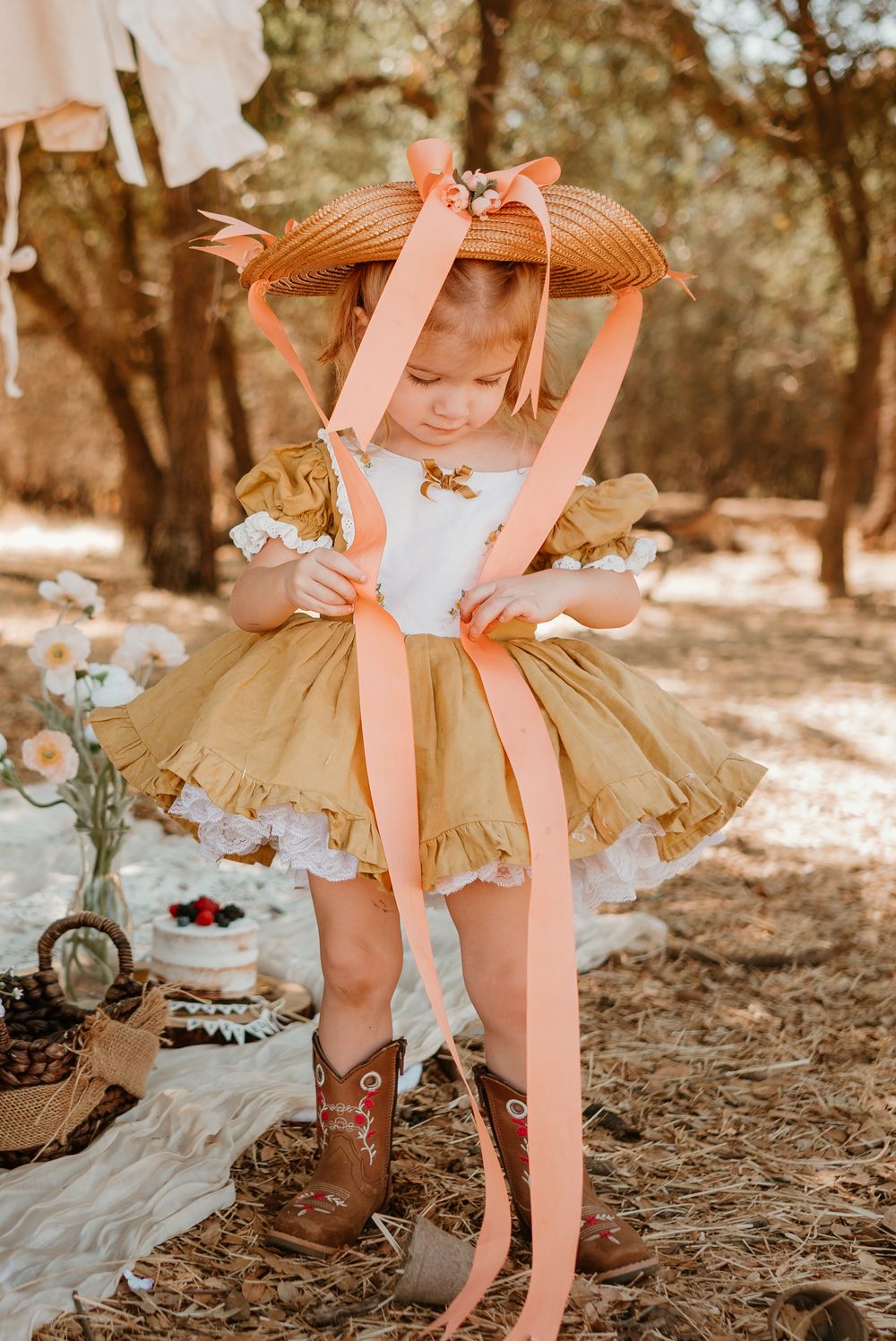 A whimsical outdoor photo series showing brown cowboy boots paired with a ruffled yellow dress and straw hat.