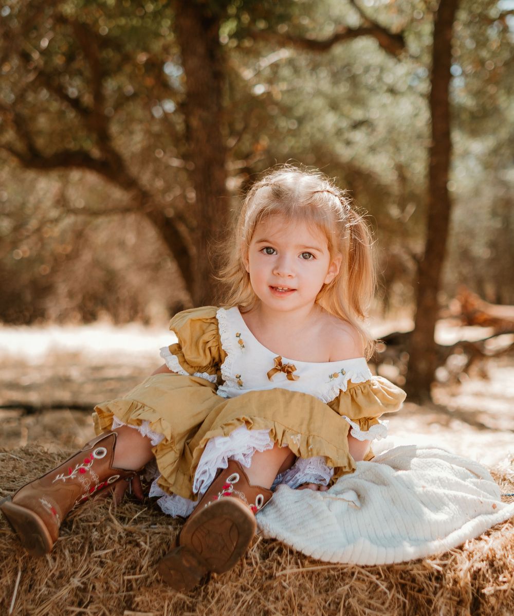 A collection of warm-toned portraits showing a child wearing a gold and white dress sitting in autumn leaves.