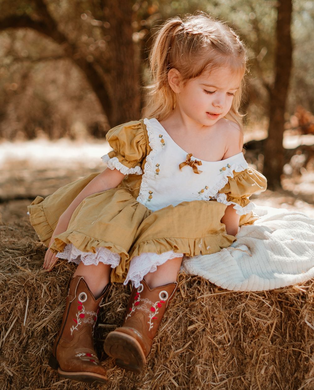 Multiple angles of cowboy boots and a yellow dress on a rustic hay bale setting with natural lighting.