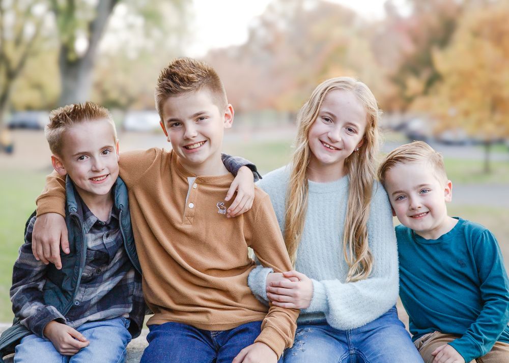 Four siblings sitting together in an autumn park in Carlisle