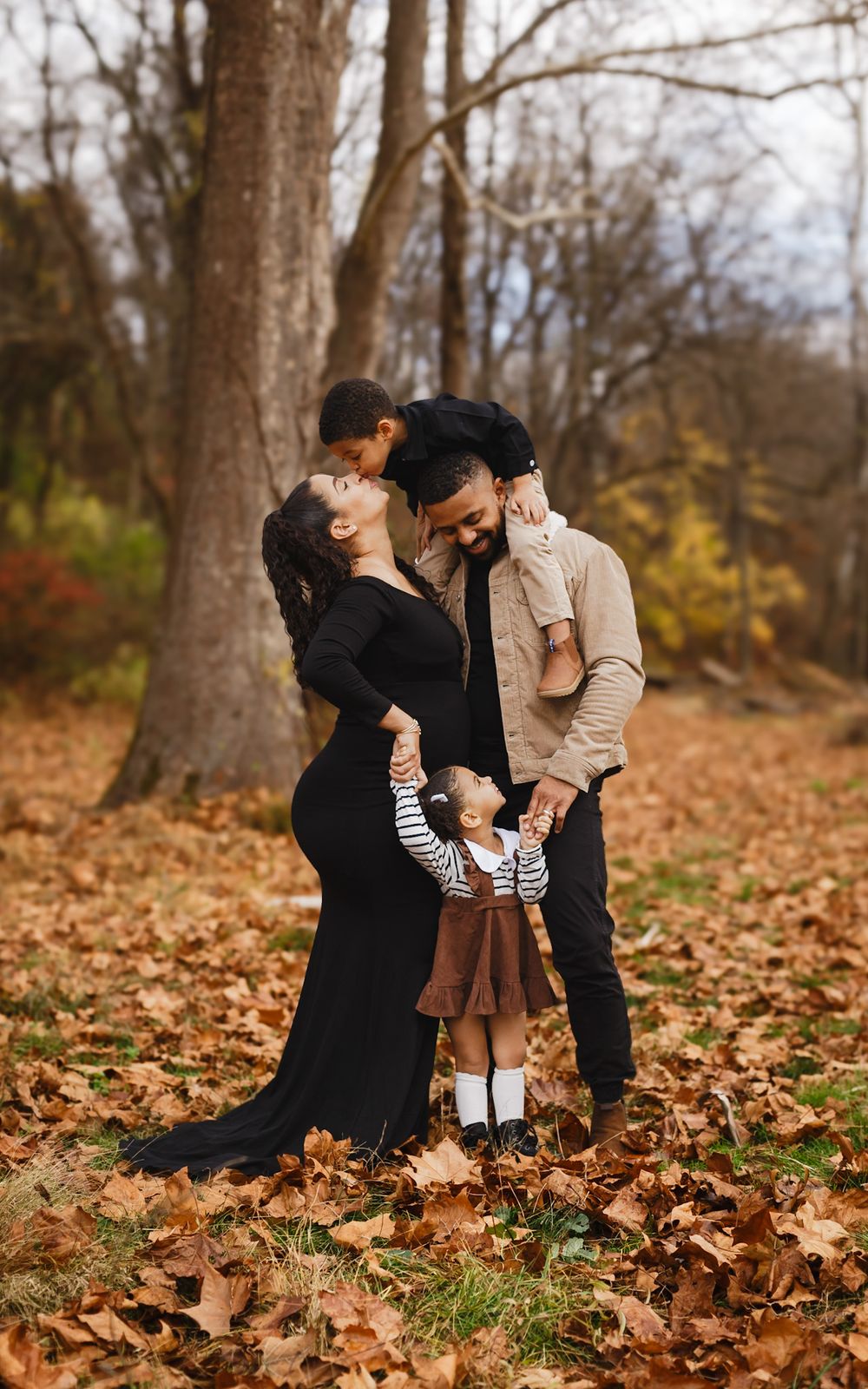 Expecting family with toddler among autumn leaves in Enola