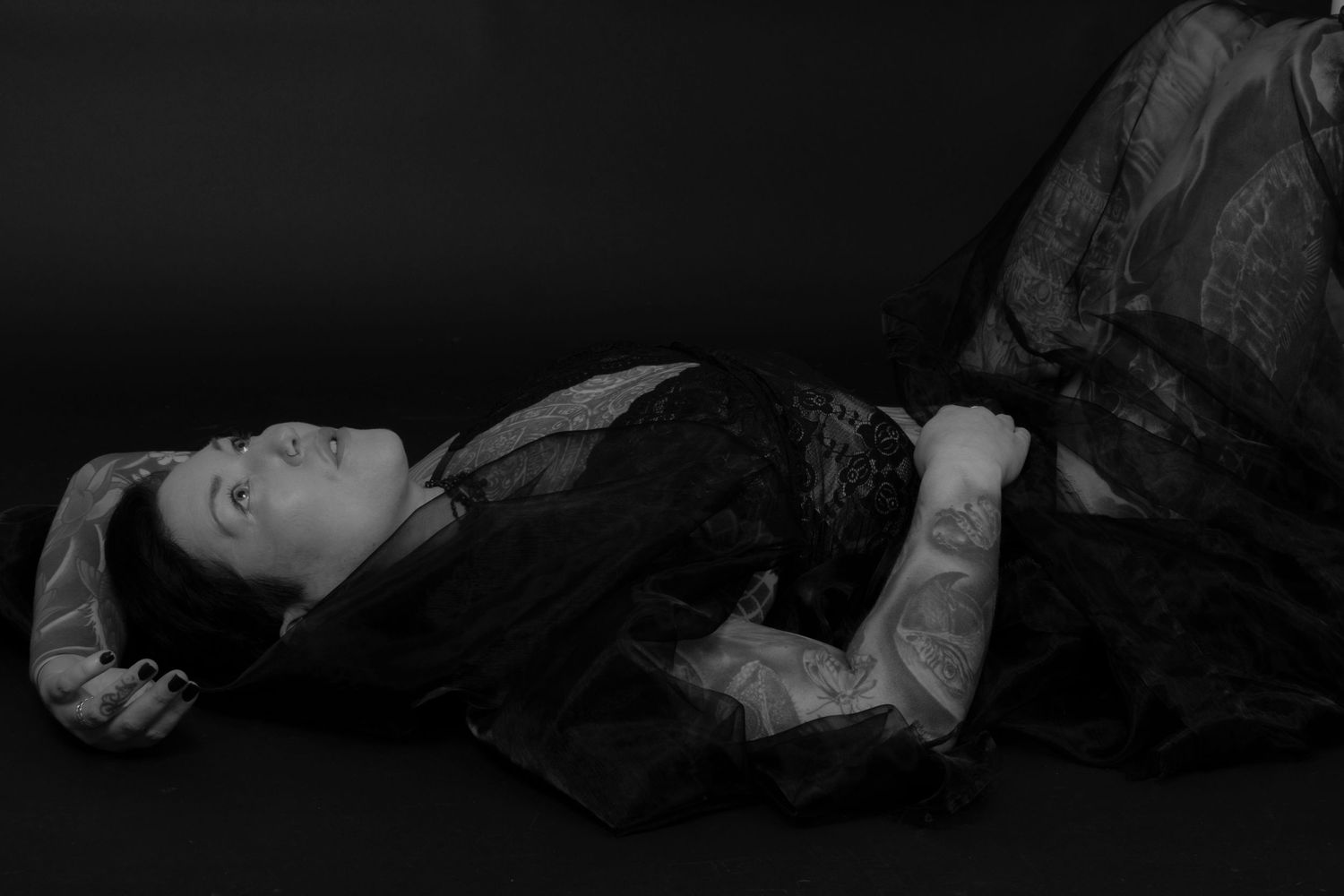 Black and white portrait of person lying down in vintage dress.