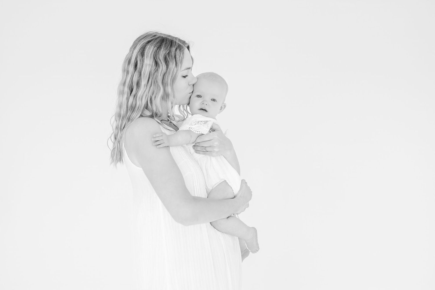 Sweet black and white portrait of mother and baby in soft lighting.