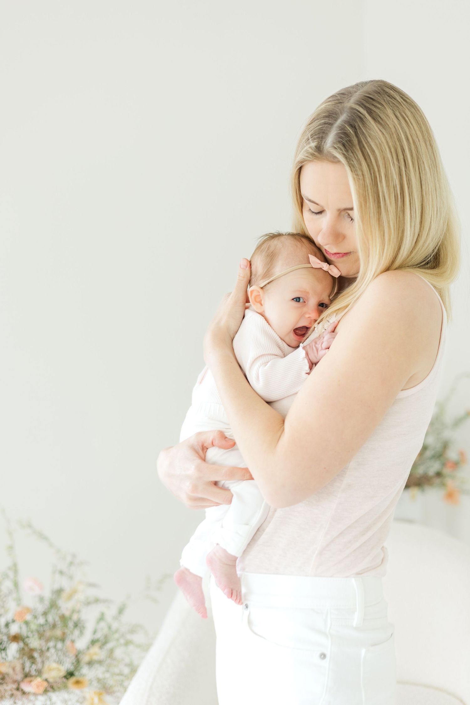 Sweet candid moments between parent and baby captured in a minimalist white studio setting.