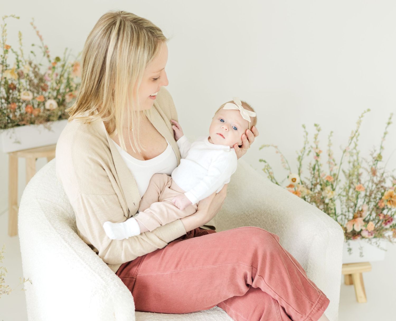 Tender parent-child portraits on white couch with soft pink and neutral tones.