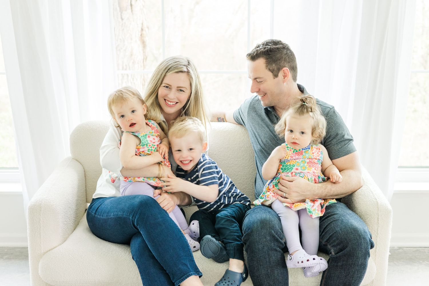 Family sitting together on white couch during casual indoor photo session.