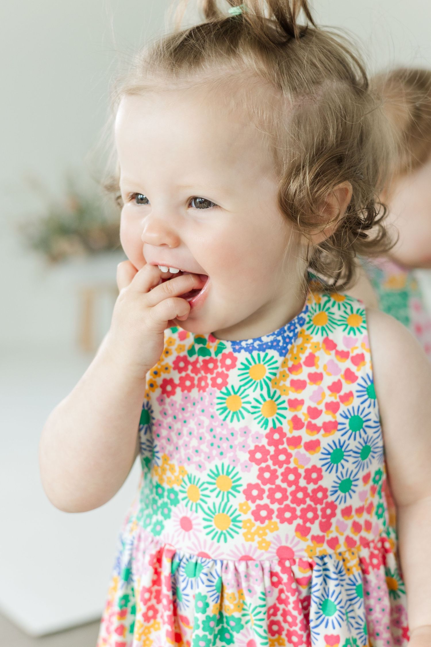 Close-up shots of toddler wearing colorful floral dress during studio photo session.