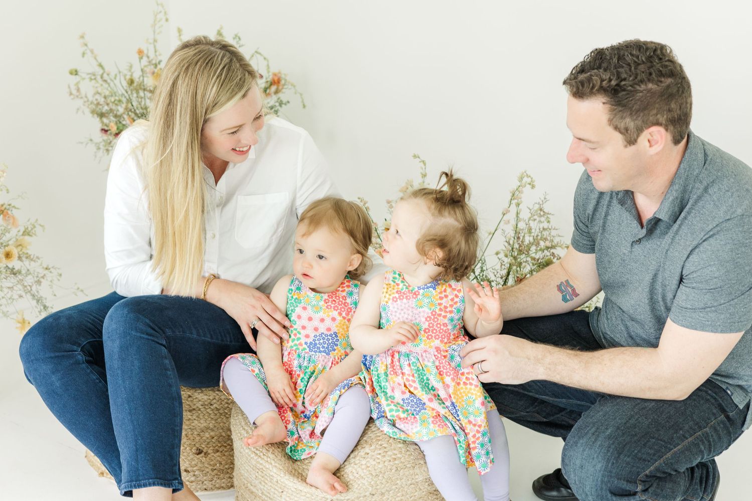 Family sitting together on a white floor with soft natural lighting and decorative elements.