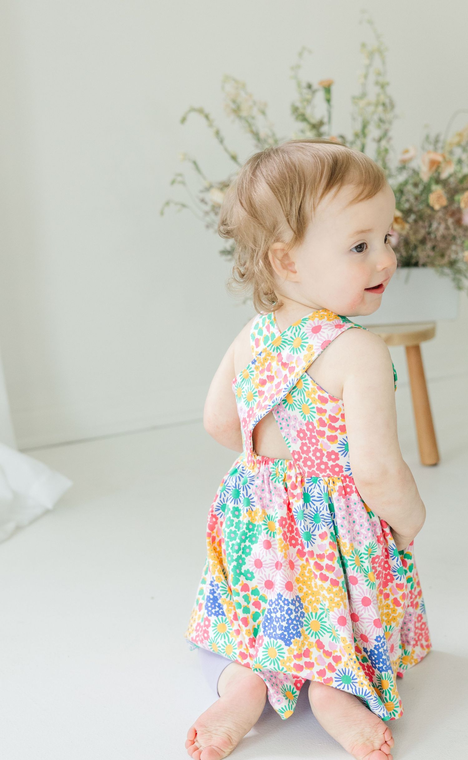 A bright floral sundress with ruffled details captured from different angles against a white backdrop.