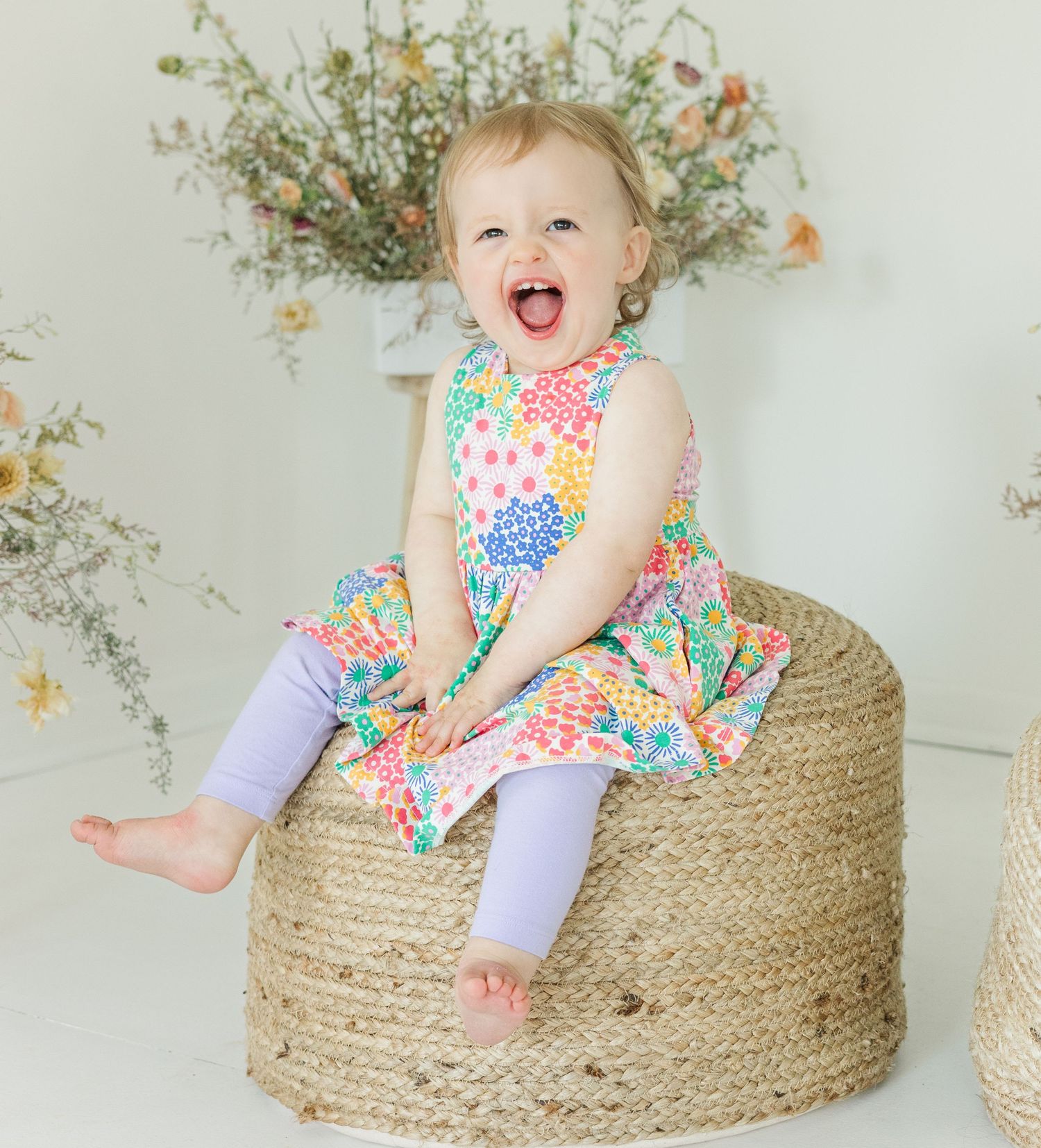 Joyful poses on a woven basket seat with floral decorations in the background.
