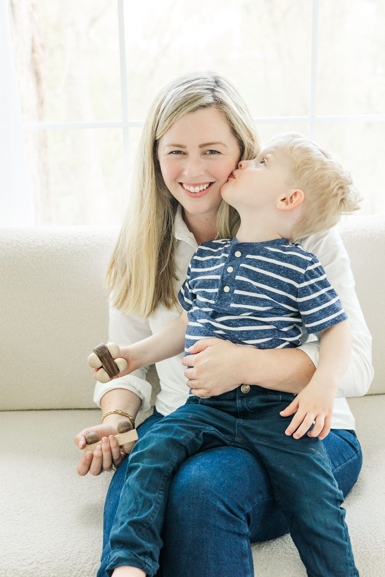 Tender family moment captured on a white couch in natural lighting.