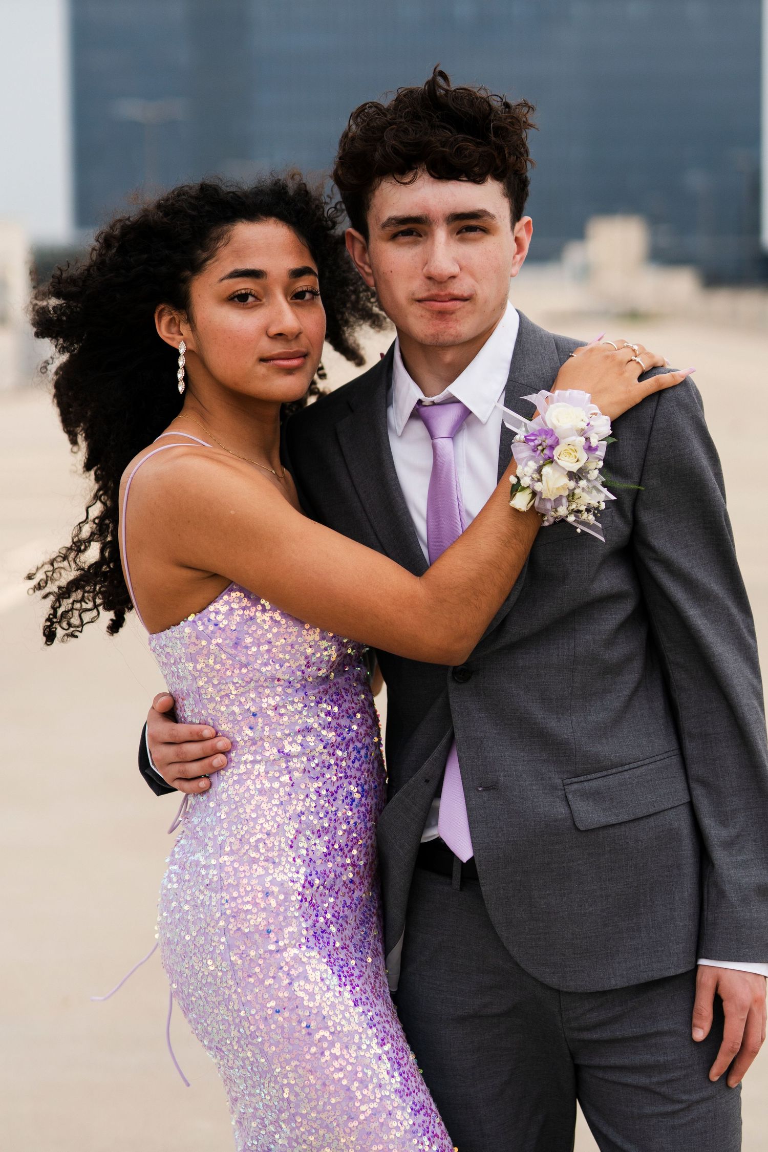 A formal portrait of a couple in prom attire with a sparkling purple dress and matching tie.