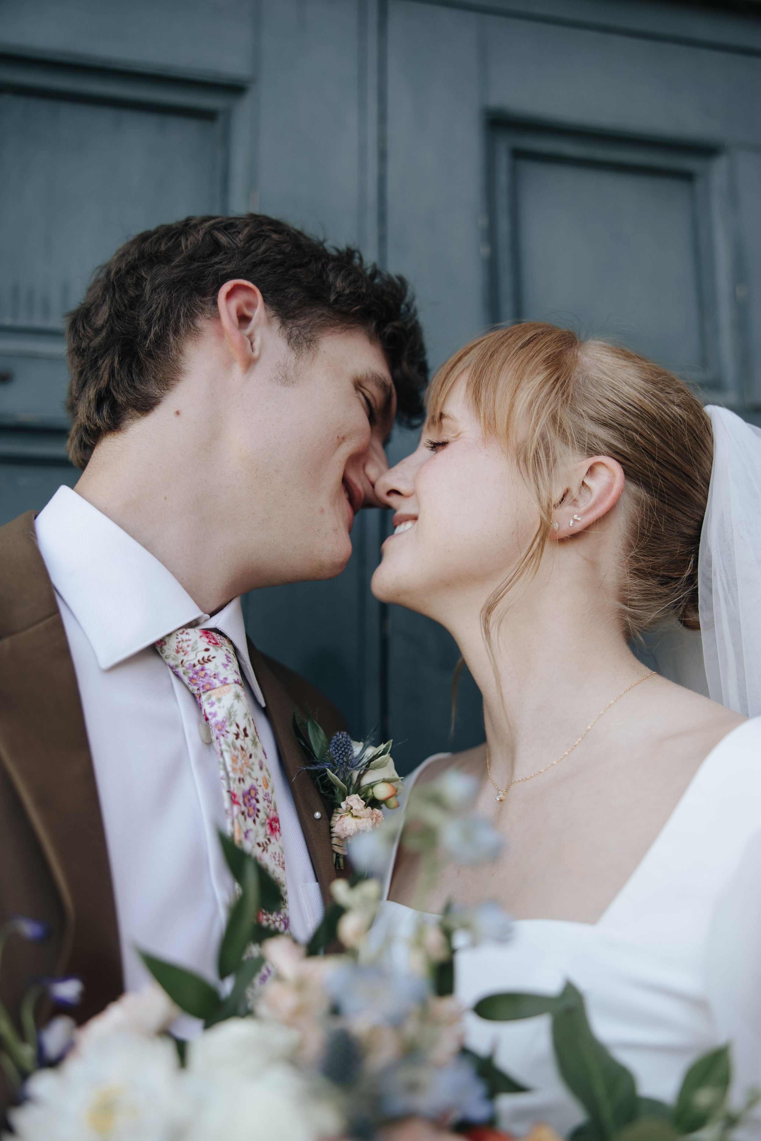 Close-up romantic wedding moment with floral bouquet in foreground.