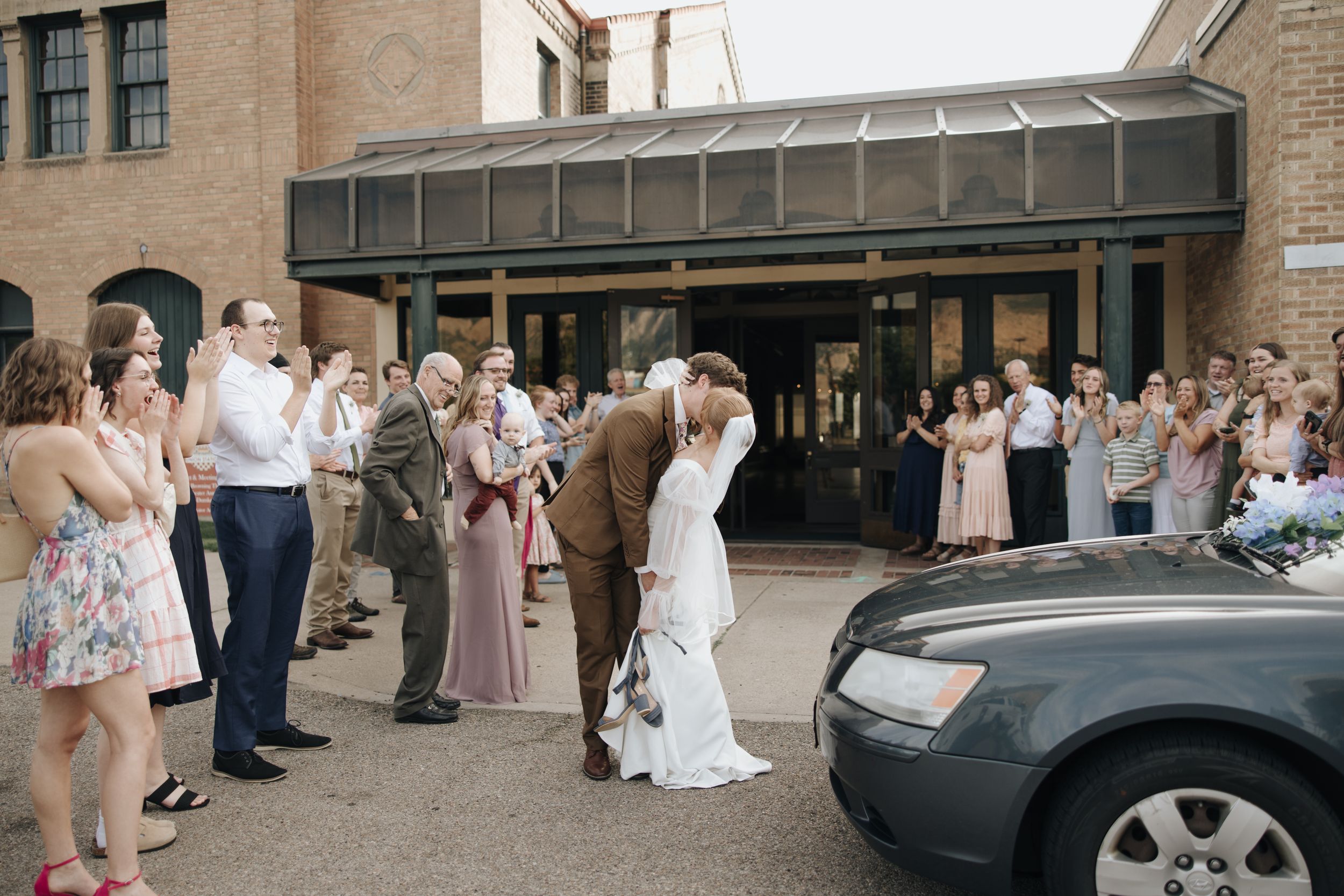 Wedding guests celebrate as newlyweds exit venue together.