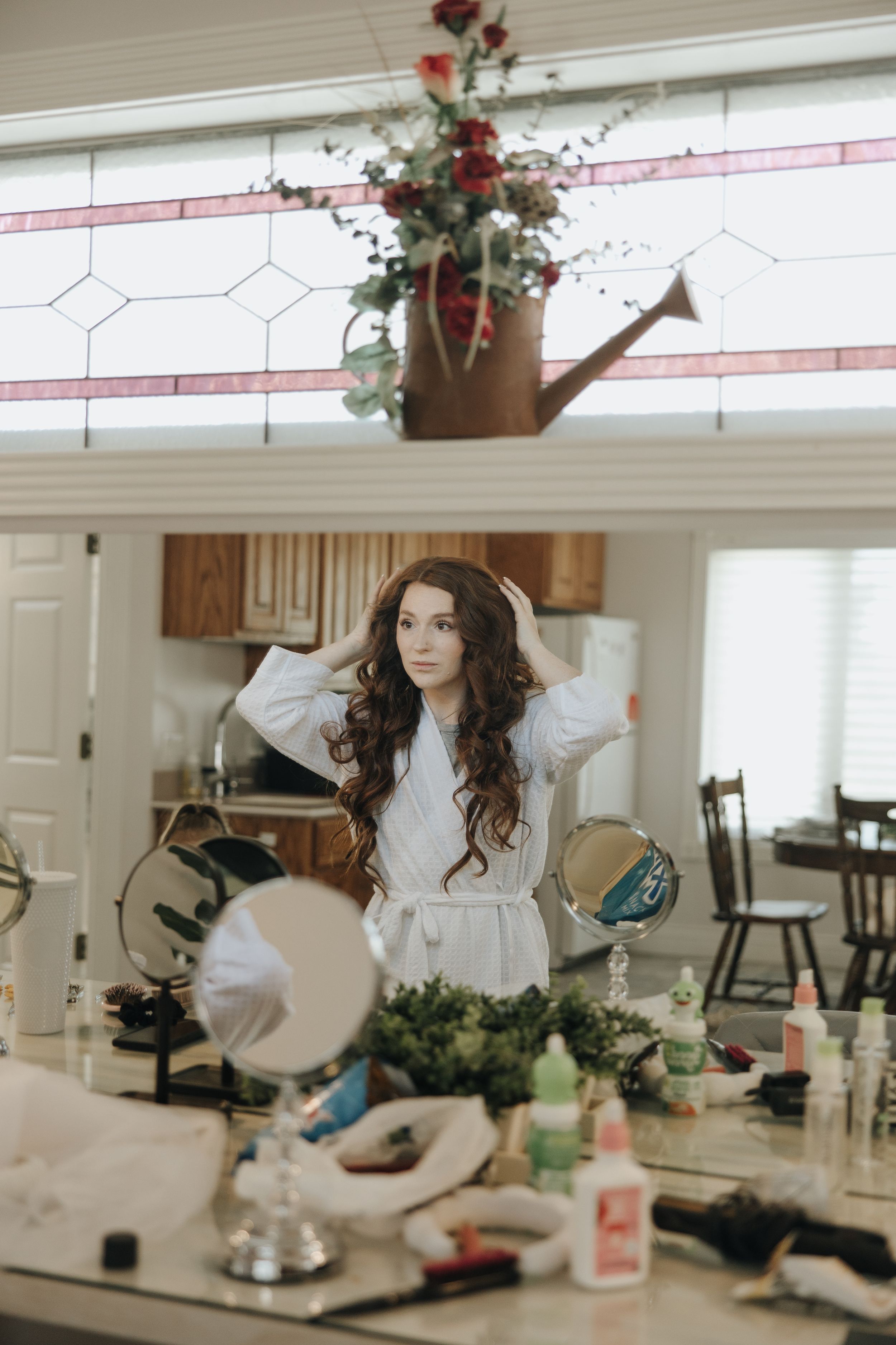 Wedding preparation scene with floral decorations and styling products on kitchen table.