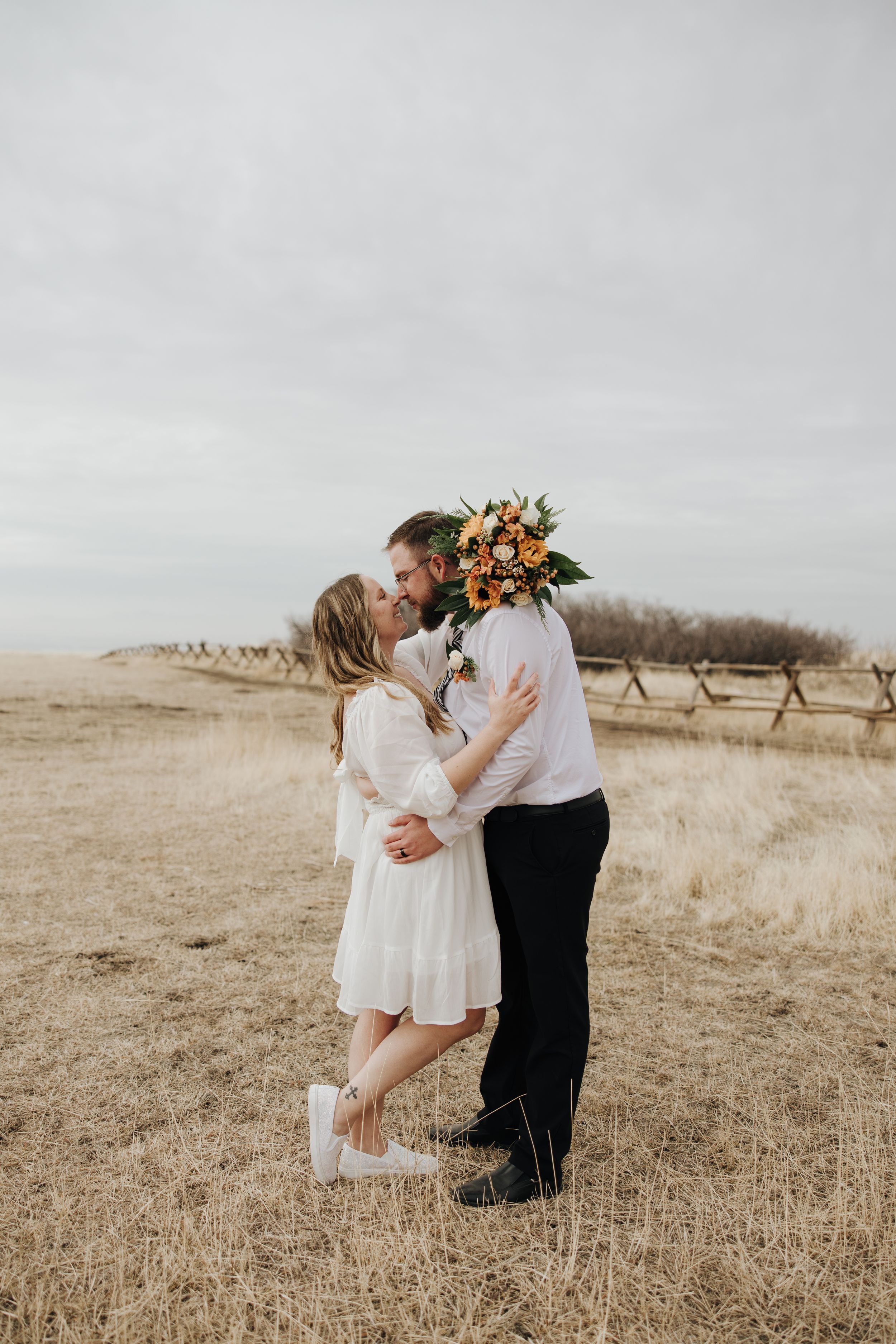 Intimate elopement portrait in golden field with couple embracing during sunset.
