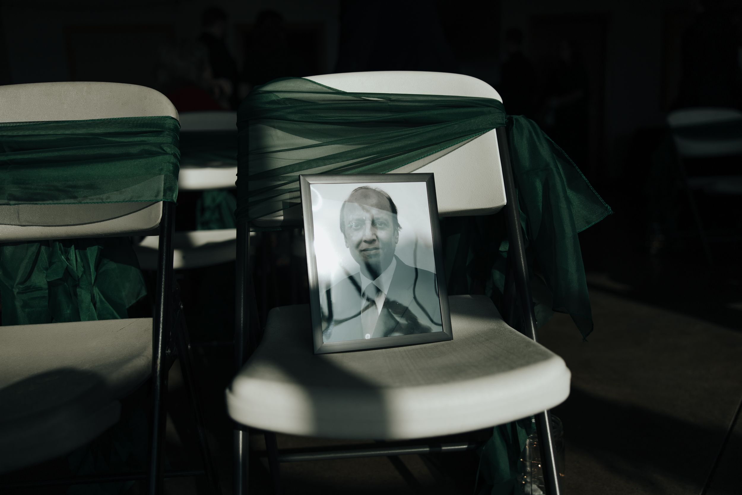 A black and white vintage portrait photograph sits on a white folding chair in a dimly lit room.