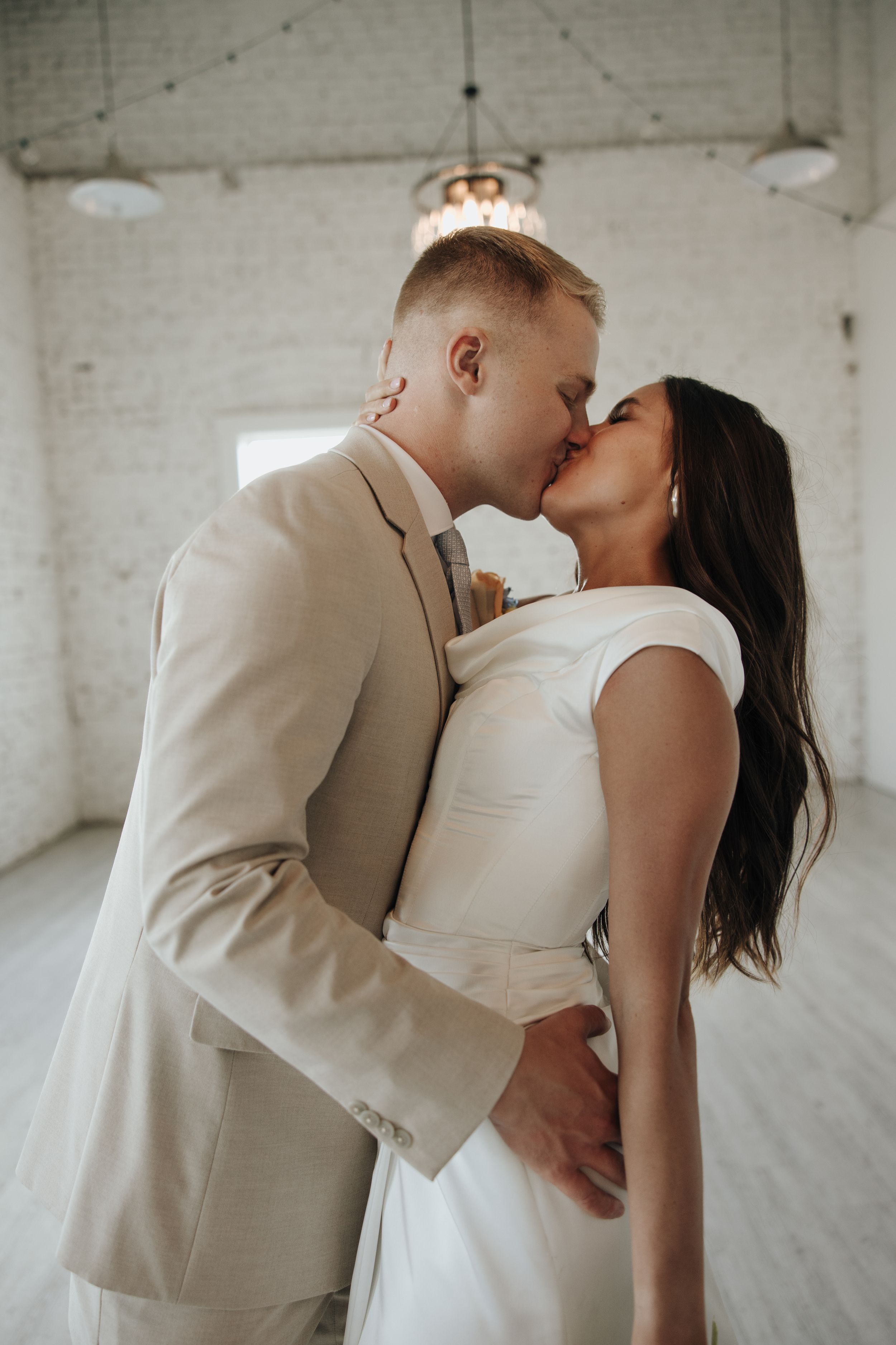 Intimate moment between newlyweds in an industrial loft space with white walls.