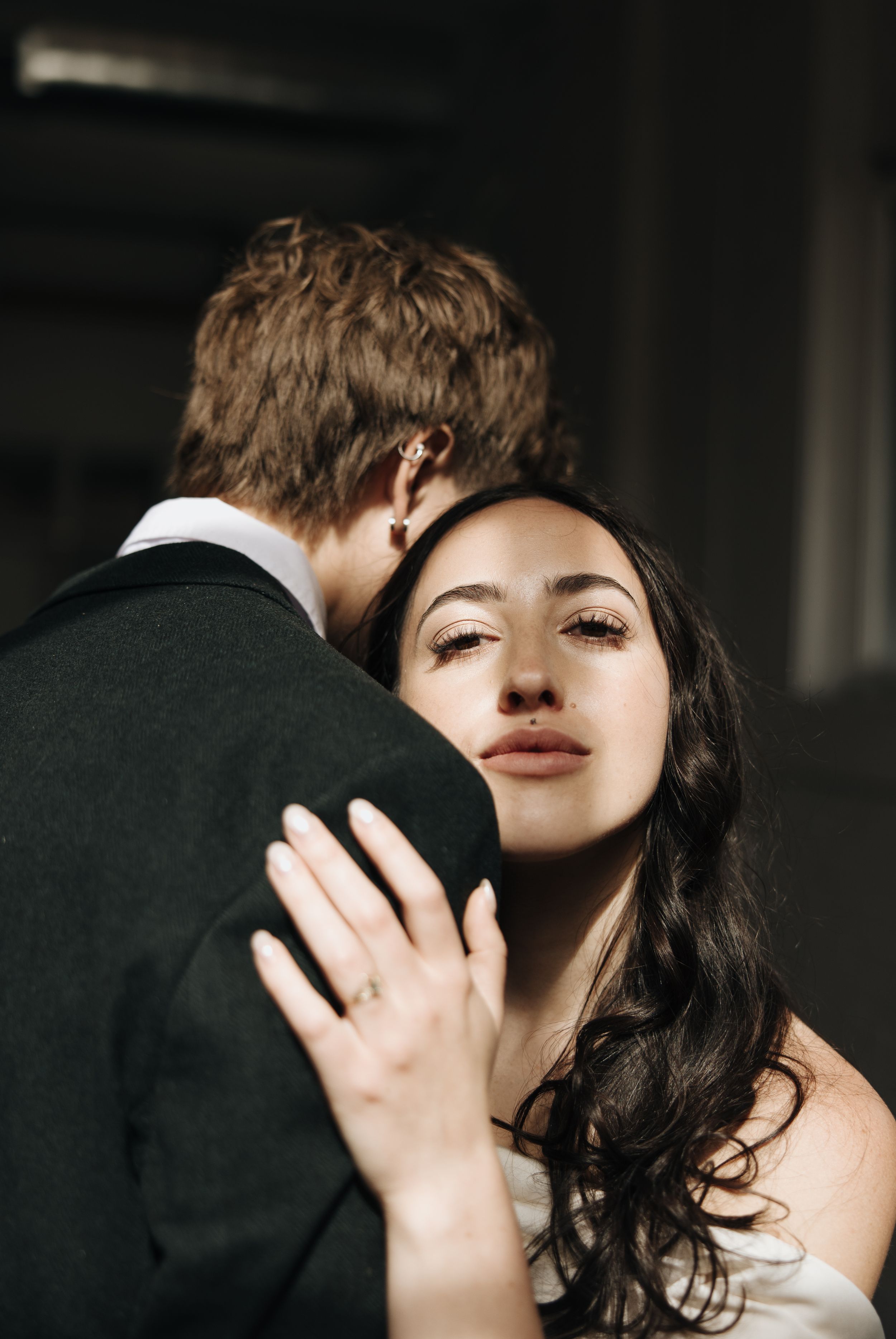 Romantic moment between couple during wedding photoshoot in dark indoor setting.