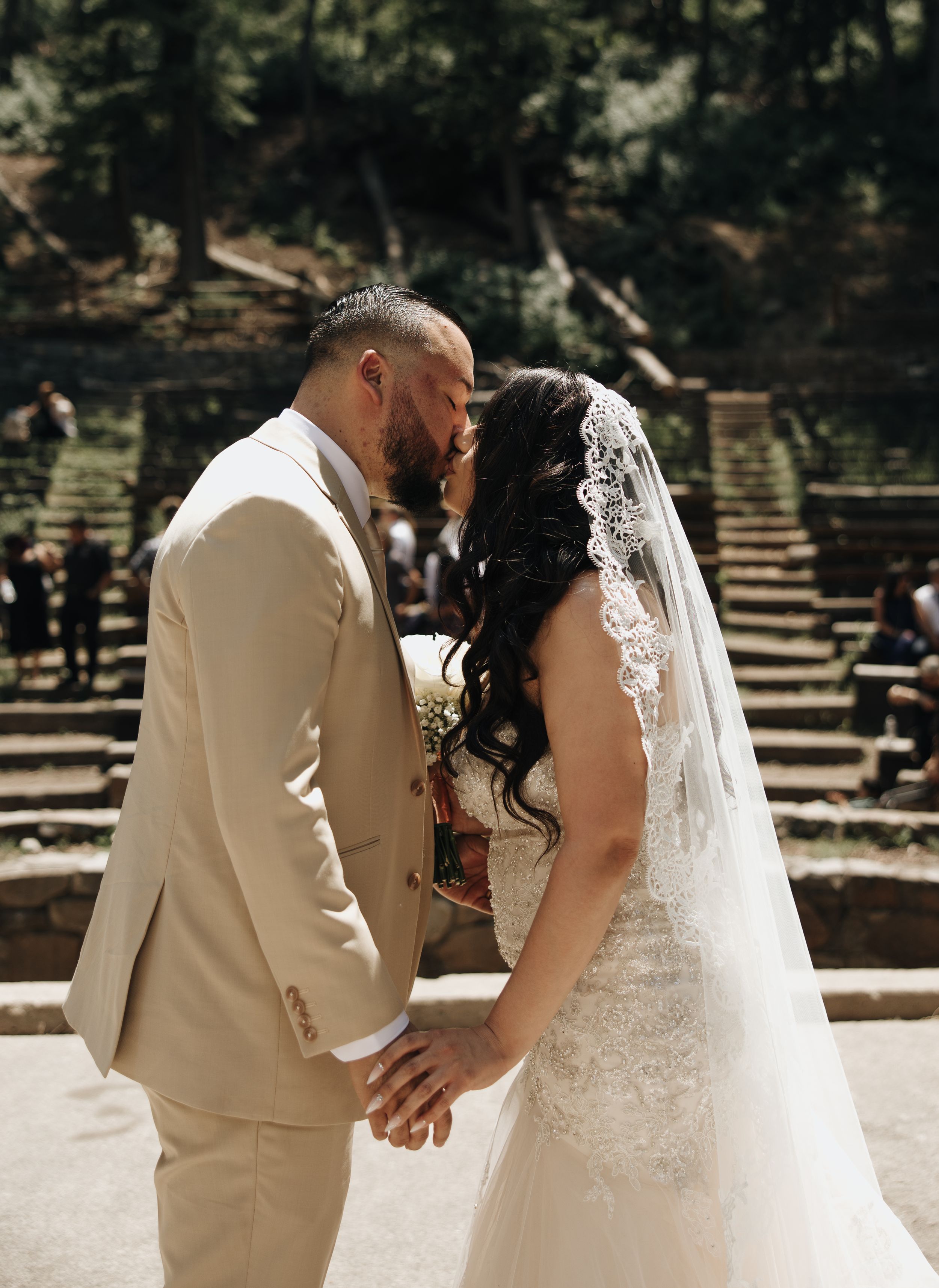 Newlyweds share intimate moment during outdoor wedding ceremony on stone amphitheater steps.