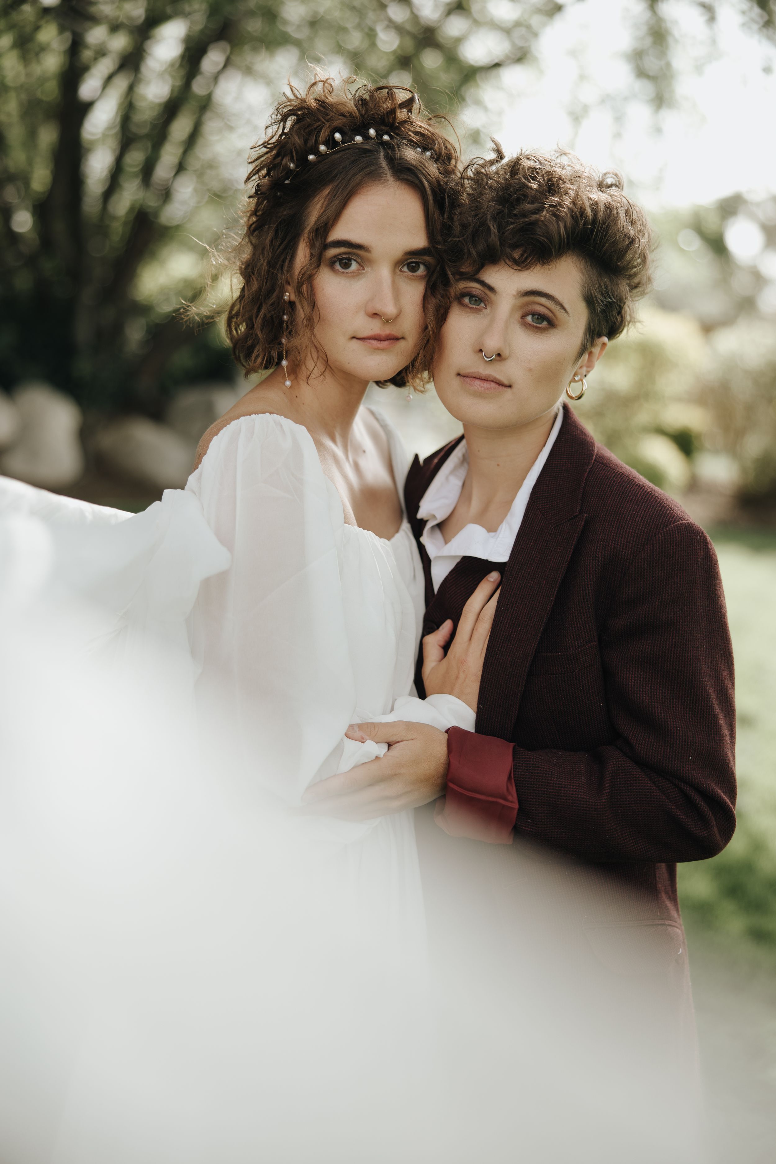 Intimate wedding portrait in garden setting with soft natural lighting and floral headpieces.
