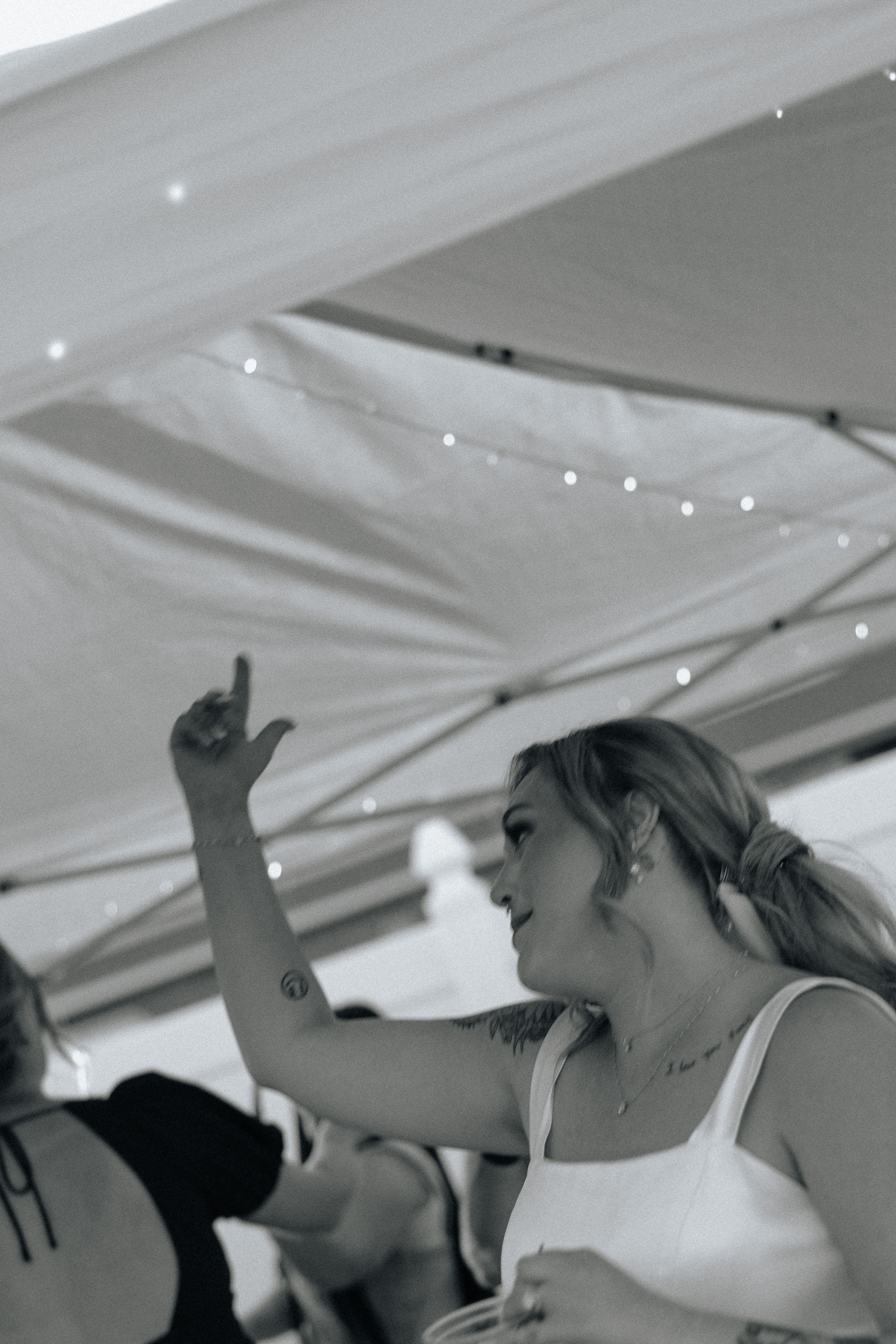 People dancing and celebrating under a tent with string lights overhead.