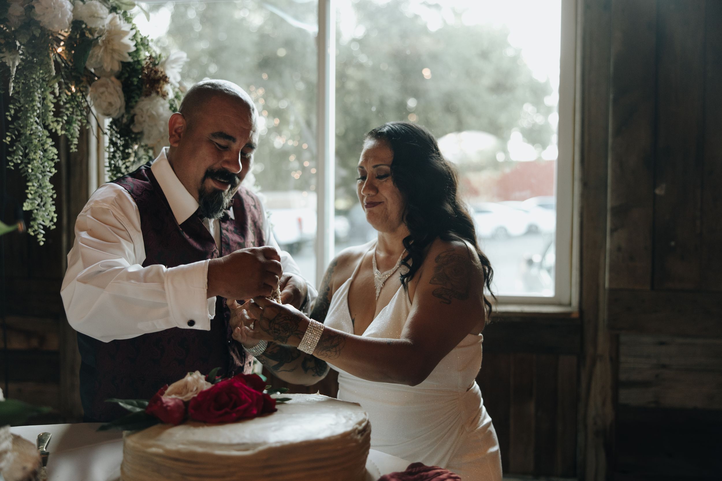 Wedding couple cutting their cake together during indoor reception.