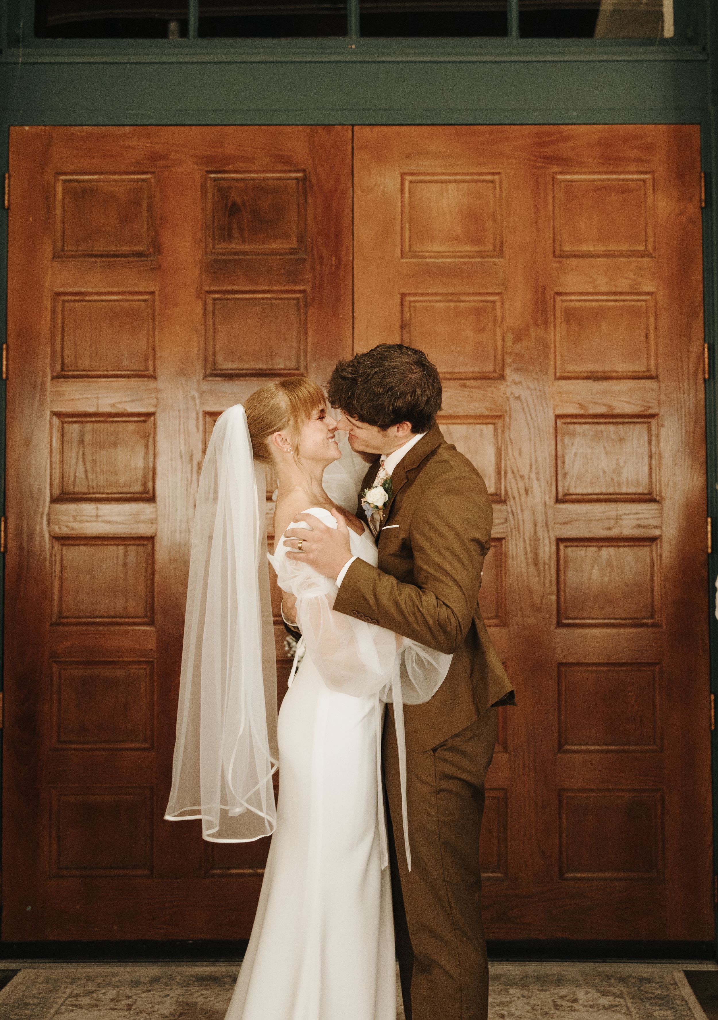 Romantic wedding portrait against wooden paneled doors.