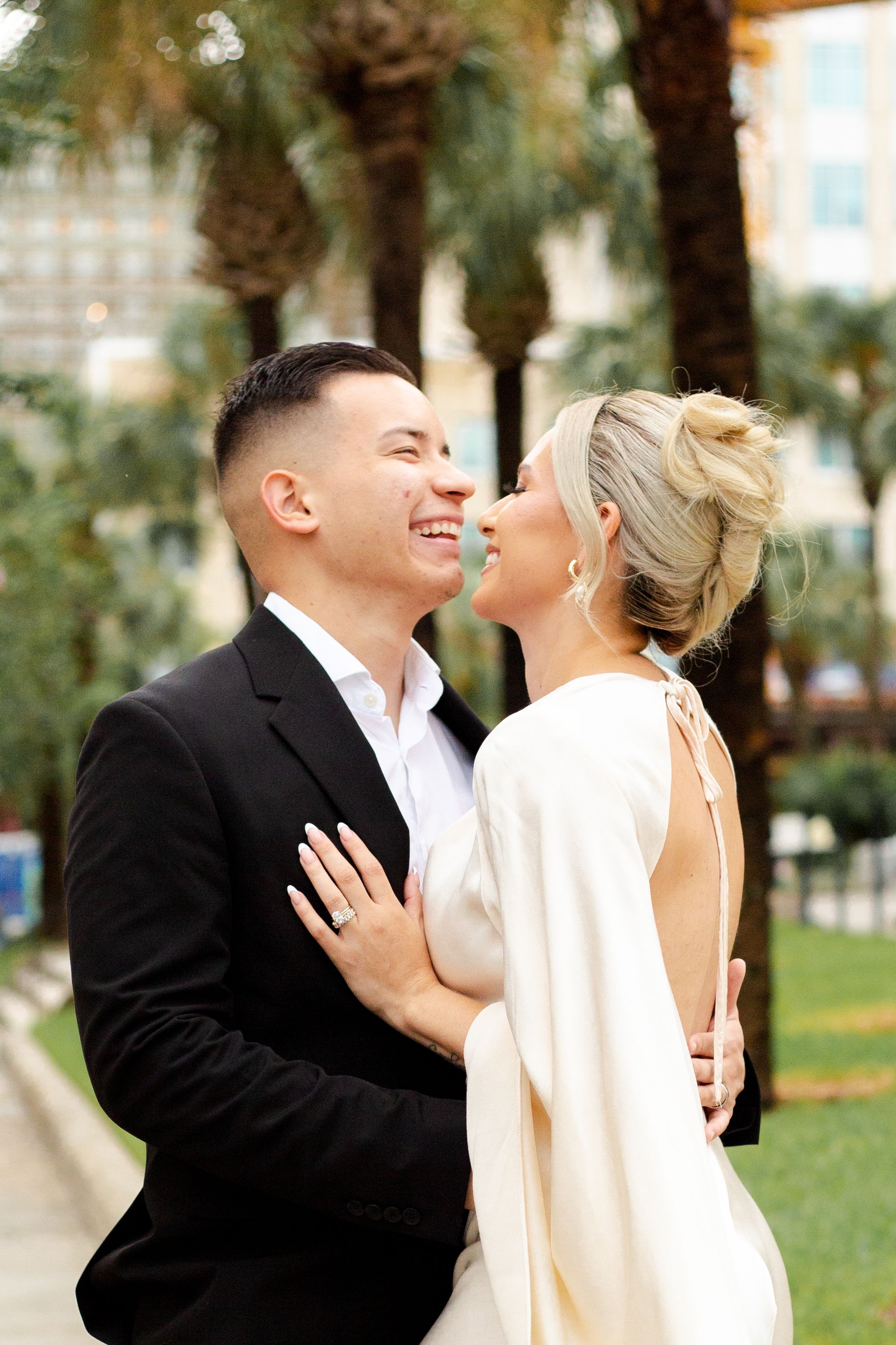 Romantic wedding portrait with palm trees showing tender moment between couple.