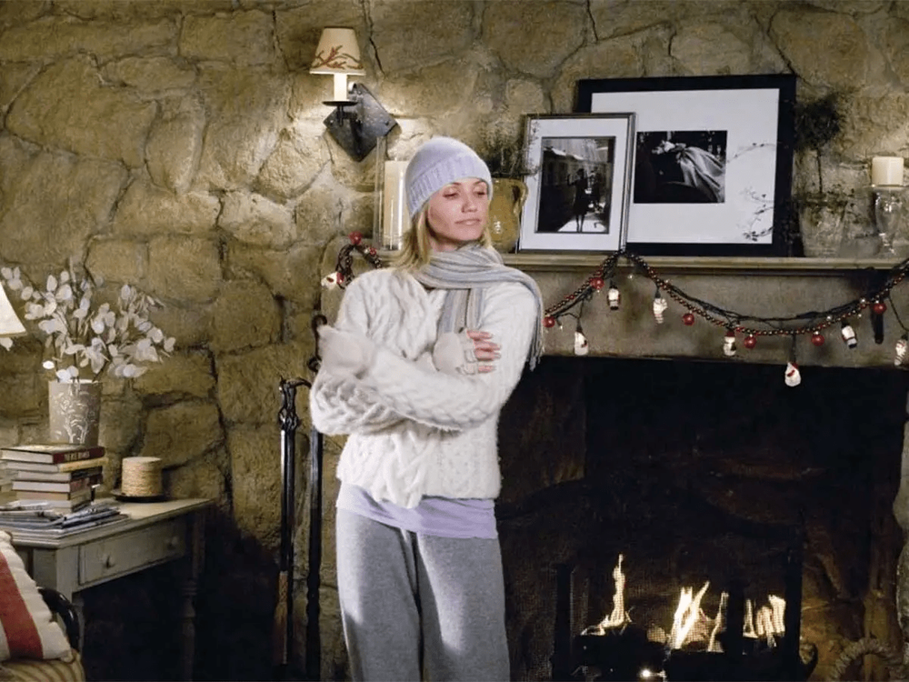 A cozy winter scene by a stone fireplace with rustic decor and string lights.