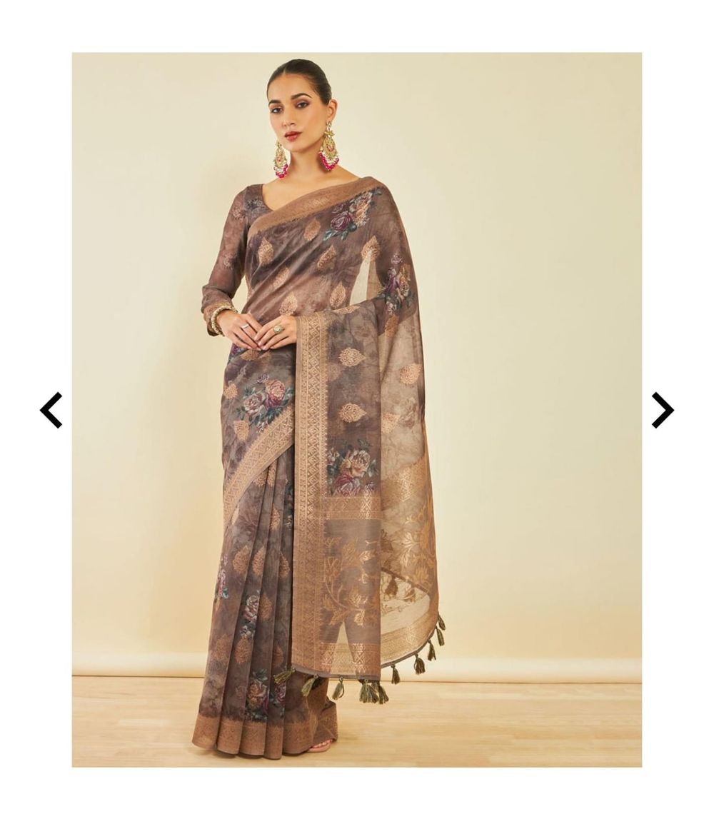 Brown floral print saree with golden border and tassels displayed on beige background.