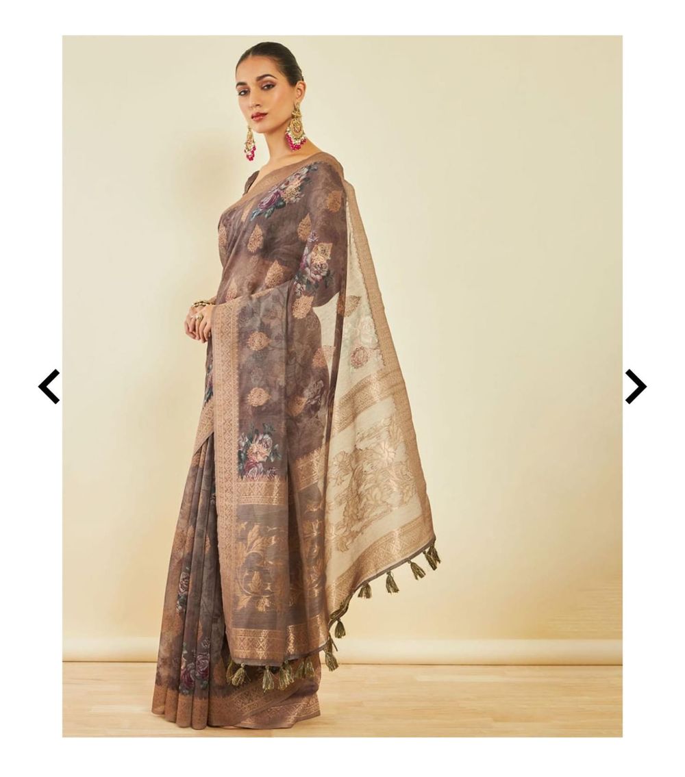 Full-length view of brown floral saree with gold border and tassel details on beige backdrop.