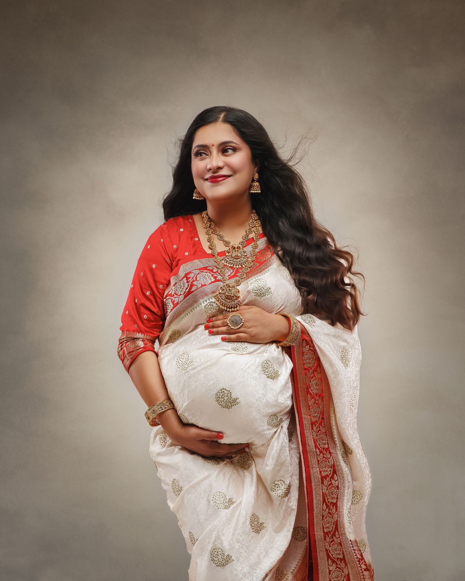 Elegant woman wearing traditional white and red embroidered sari with long flowing dark hair against neutral background.