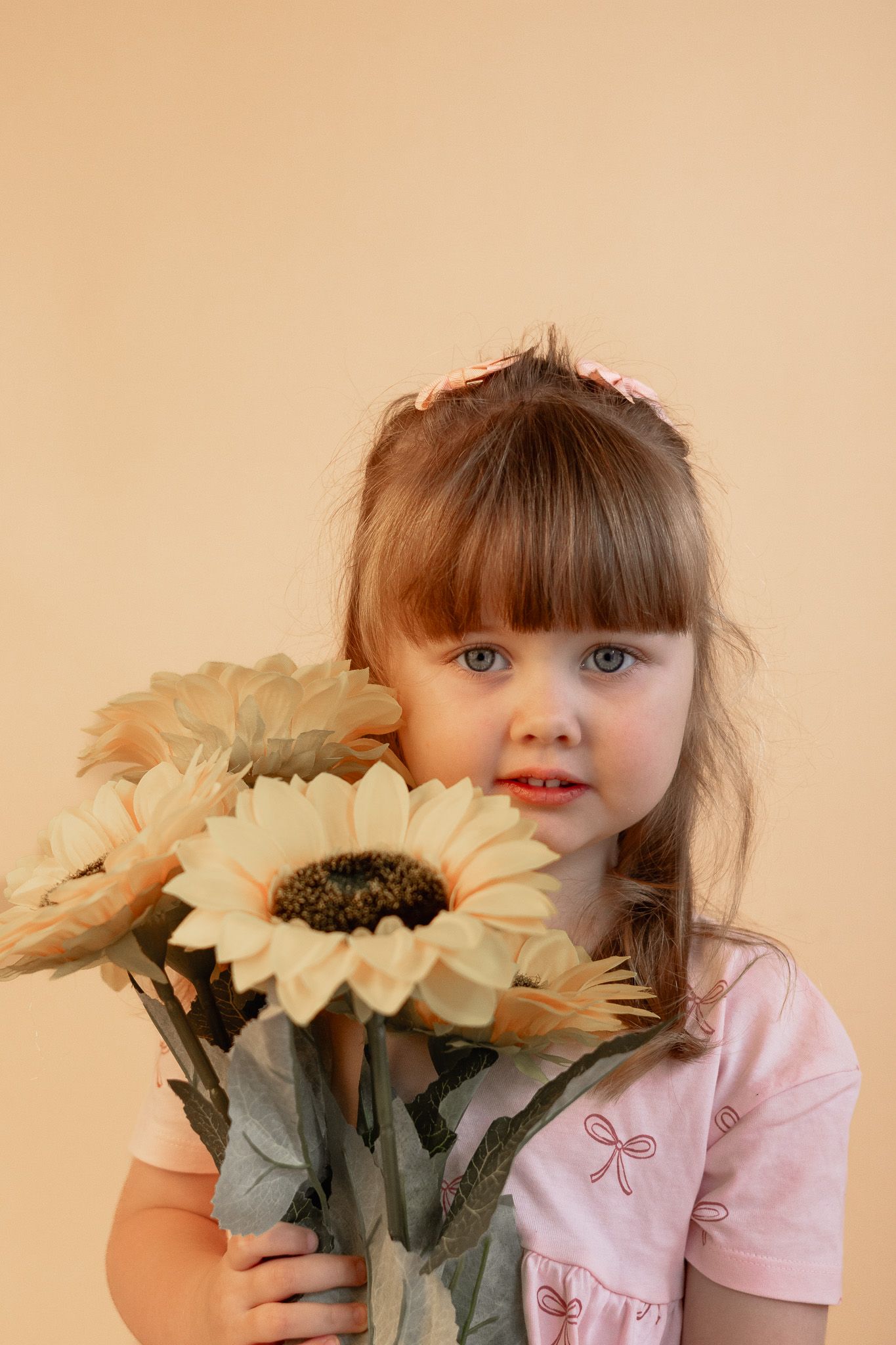 Portrait with silk sunflowers against a peachy backdrop.
