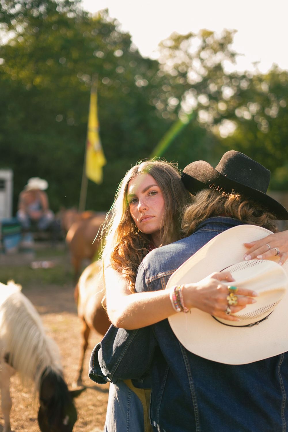 Couple in cowboy hats sharing intimate moment at rustic outdoor setting.