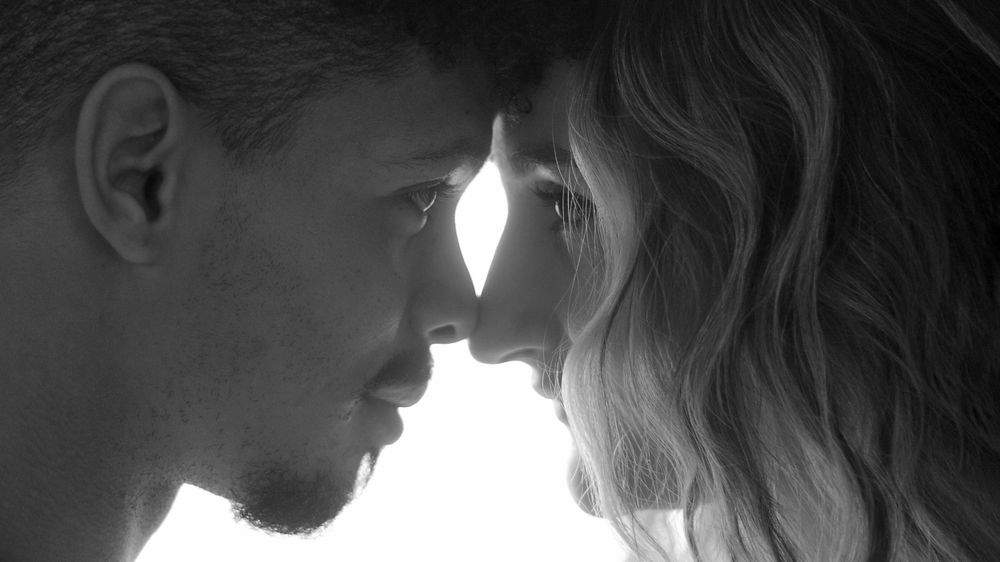 An intimate black and white close-up portrait of two people nearly touching foreheads.