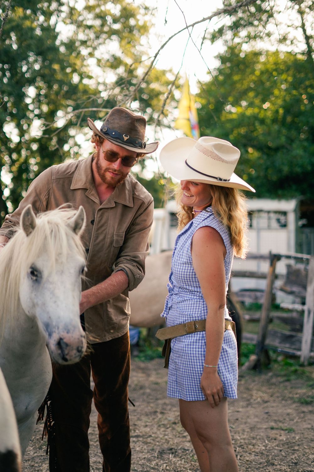 People with white horse at rustic farm setting in evening light.