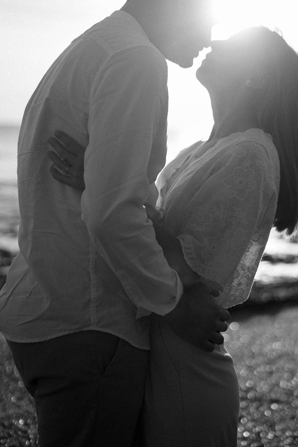 A silhouetted couple in a romantic embrace against bright backlight.