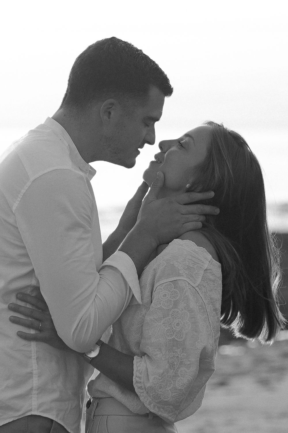 An intimate black and white portrait of a couple sharing a tender moment.
