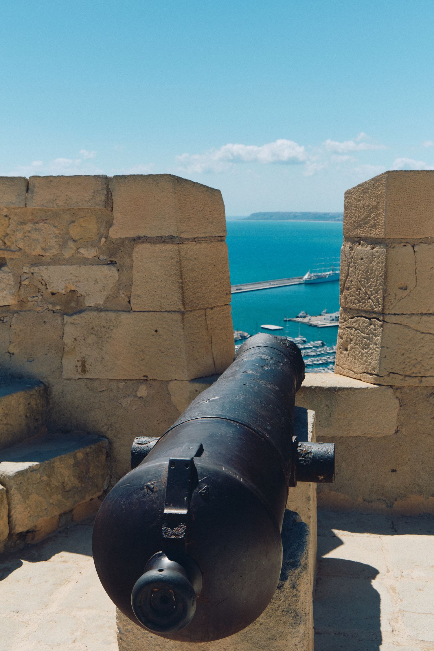Historic black cannon positioned between stone walls overlooking the Mediterranean Sea.
