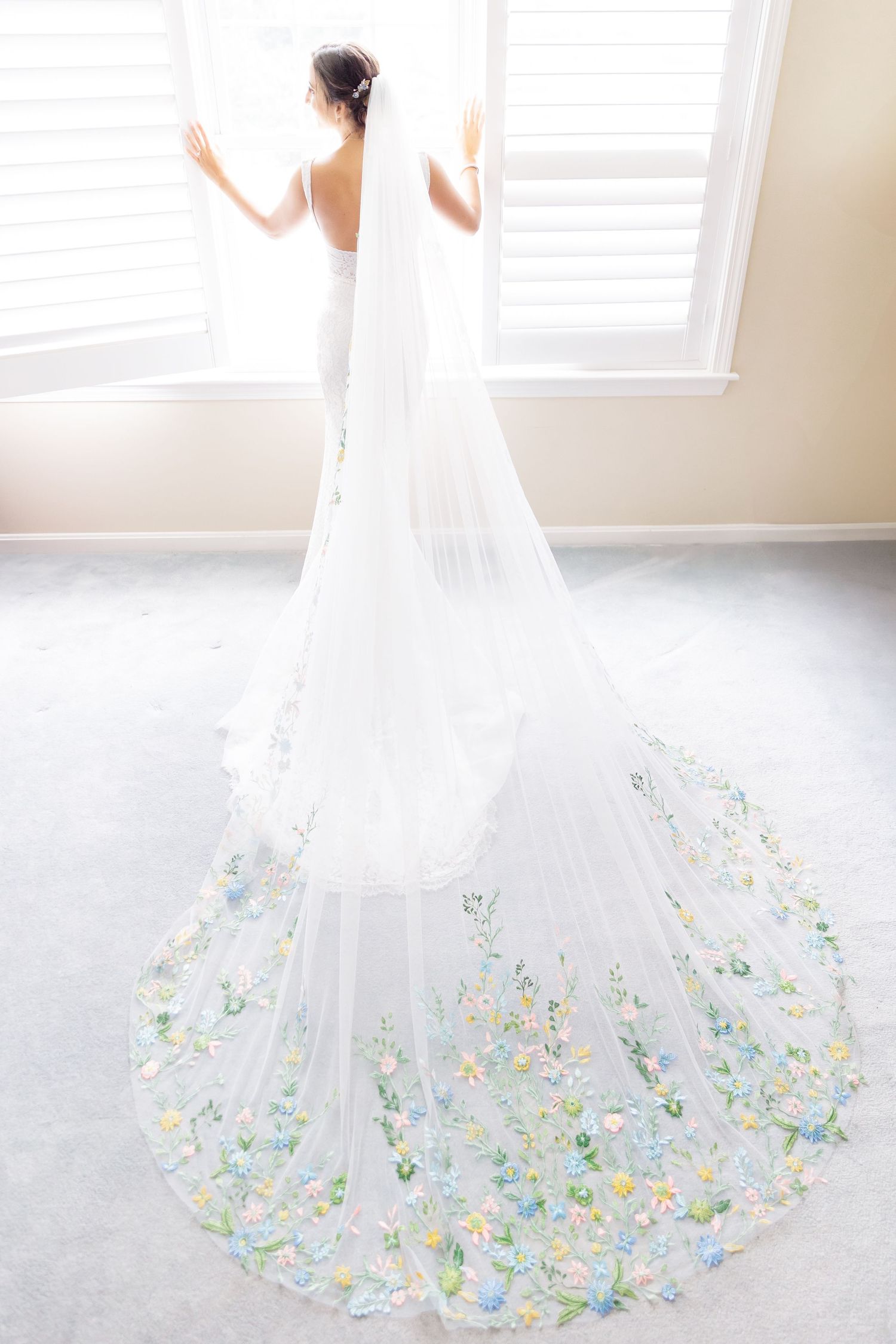 Wedding dress with floral embellished train photographed in natural window light.