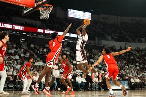 College basketball player drives to the hoop against defenders in a packed arena during an intense NCAA game.