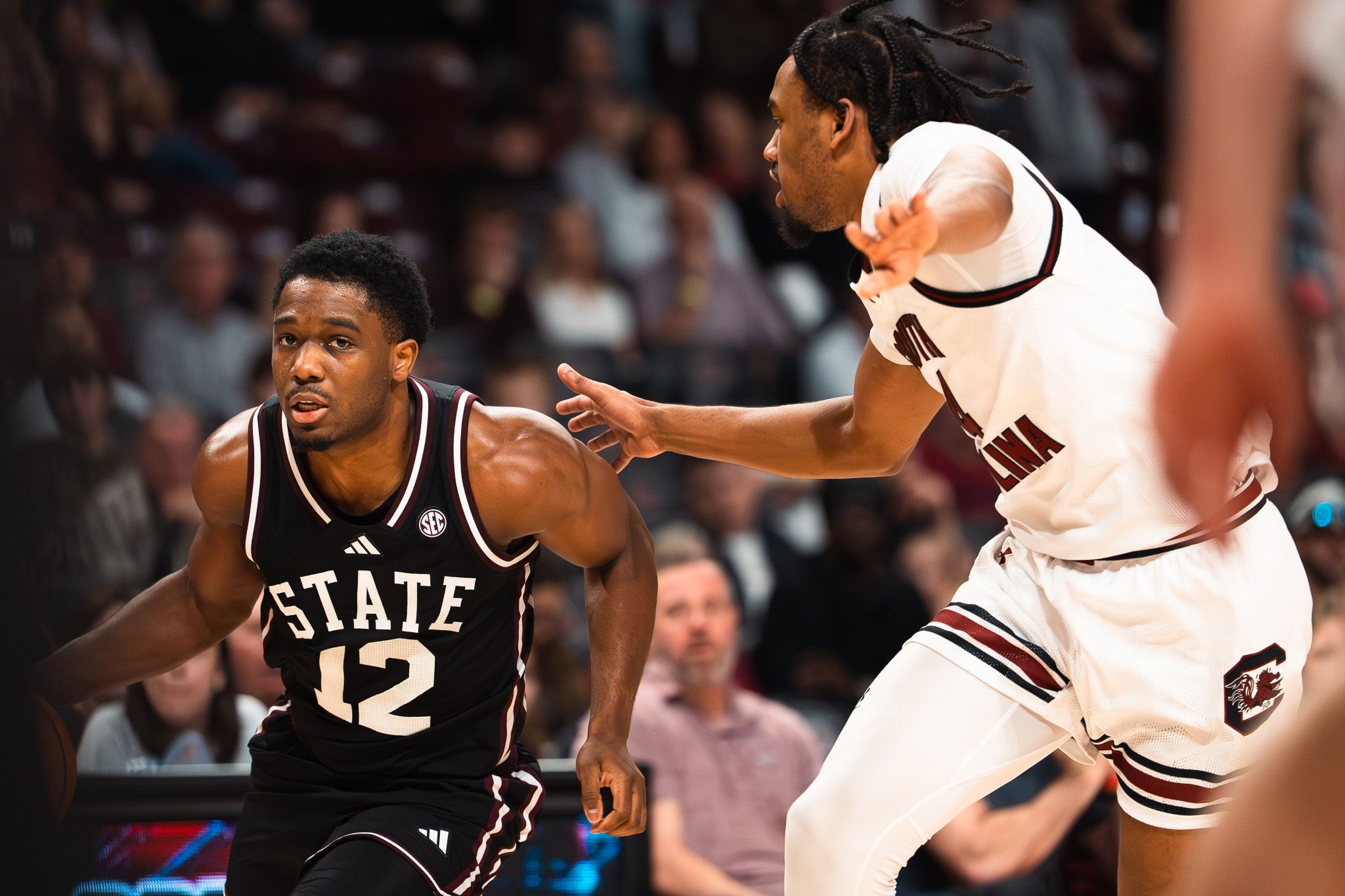 Mississippi State Bulldogs player #12 posts up against a South Carolina Gamecocks defender during a college basketball game.