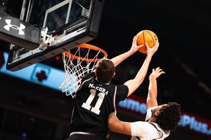 Basketball player #11 McCoy blocks a shot attempt near the hoop during a college game.